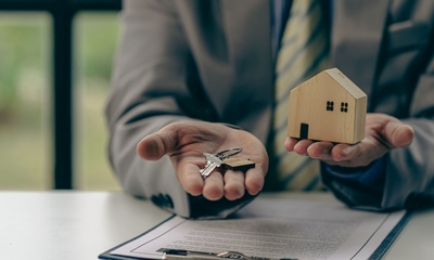 Agent holding newly purchased house key and miniature home